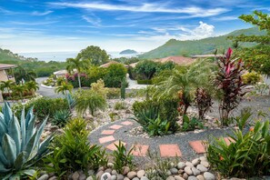 Stroll through a serene garden with a pebble pathway leading to charming buildings with red-tiled roofs.
