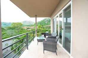 Enjoy the serene view from this balcony with a sofa and table, perfect for taking in the surrounding landscape.