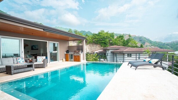 Ein Pool mit Liegebereich, Essbereich und Blick auf Hügel.