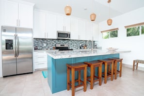Enjoy cooking in this well-equipped kitchen with a large refrigerator, microwave, and island with bar stools.