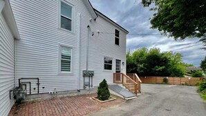 Une maison à deux étages avec une allée pavée en briques et un petit arbre devant.