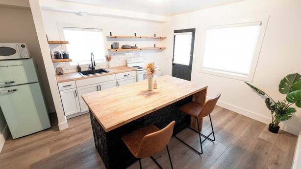 Une cuisine moderne avec des armoires blanches, un îlot central en bois et une cuisinière intégrée.