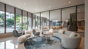 A modern hotel lobby with a curved sofa, round coffee table, and seating area. Large windows offer views of the street and greenery. - Crownshine Resort (Jiaoxi)