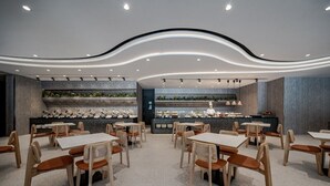 A modern restaurant with a central bar area, multiple seating arrangements, and a contemporary ceiling design. - Crownshine Resort (Jiaoxi)