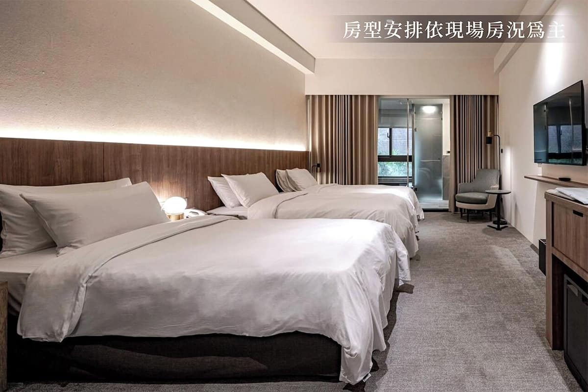A hotel room with two beds, a TV, a desk, and a chair.