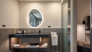 A modern bathroom with a round mirror, dual sinks, and a glass shower enclosure. - Crownshine Resort (Jiaoxi)