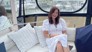 A woman seated on a white cushioned bench with a view of a marina through a large window. - Floating 2 bed 2 bath condo stunning views of the bay  (Stevensville)