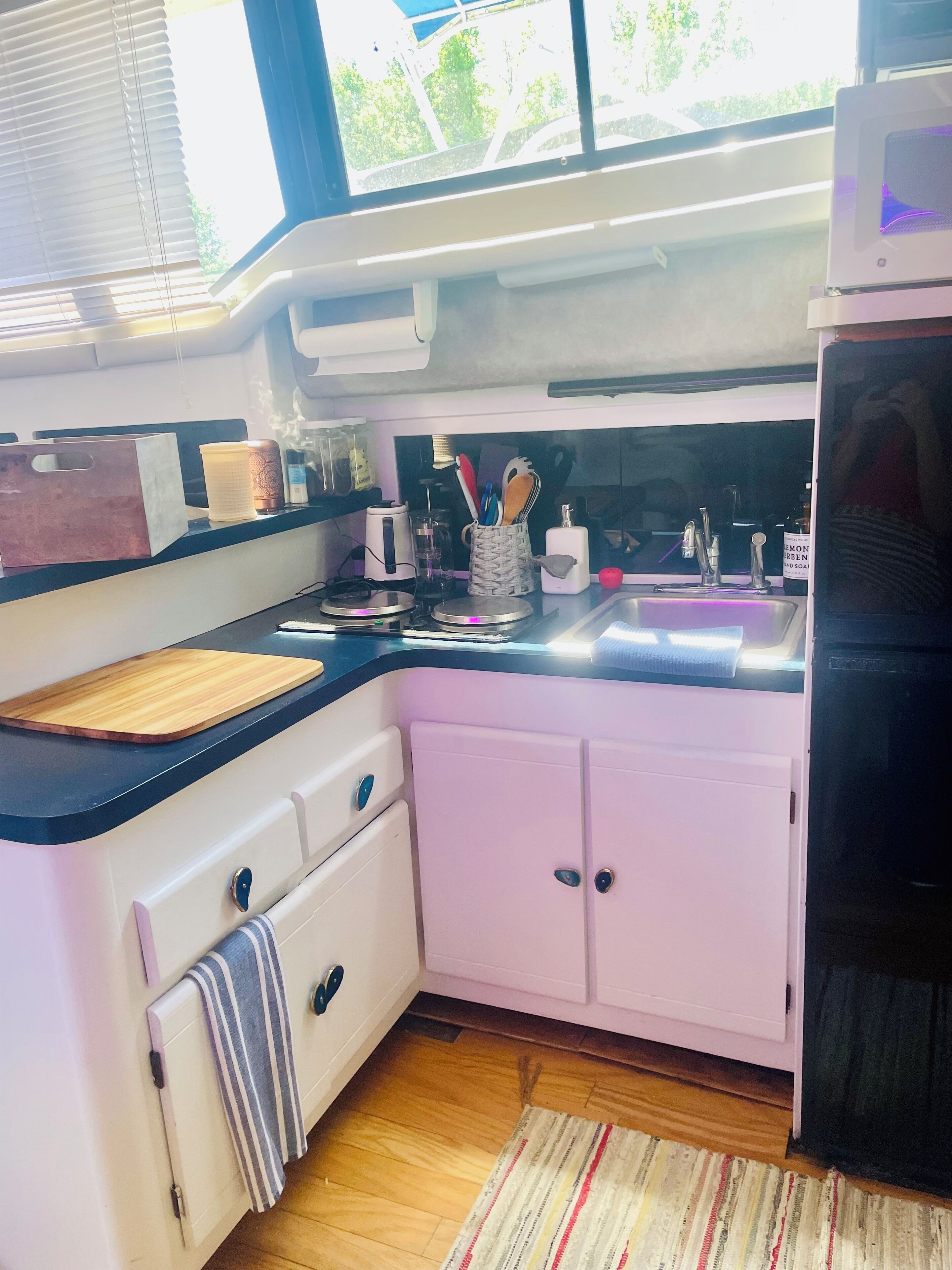 A compact kitchen with a microwave, sink, and wooden countertop.