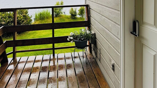 A wooden deck with a view of a body of water, a white door, and a small potted plant. - Oceanfront🔹Abundant Wildlife Viewing Opportunities🔹Local Native Owners (Ketchikan)