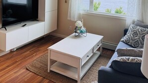 A living room with a TV on a white cabinet, a coffee table, a sofa, and a window with a view of the sea. - Oceanfront🔹Abundant Wildlife Viewing Opportunities🔹Local Native Owners (Ketchikan)