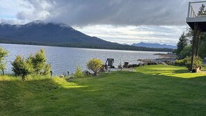 A grassy area with a view of a lake and mountains. There is a chair and a small structure. - Oceanfront🔹Abundant Wildlife Viewing Opportunities🔹Local Native Owners (Ketchikan)