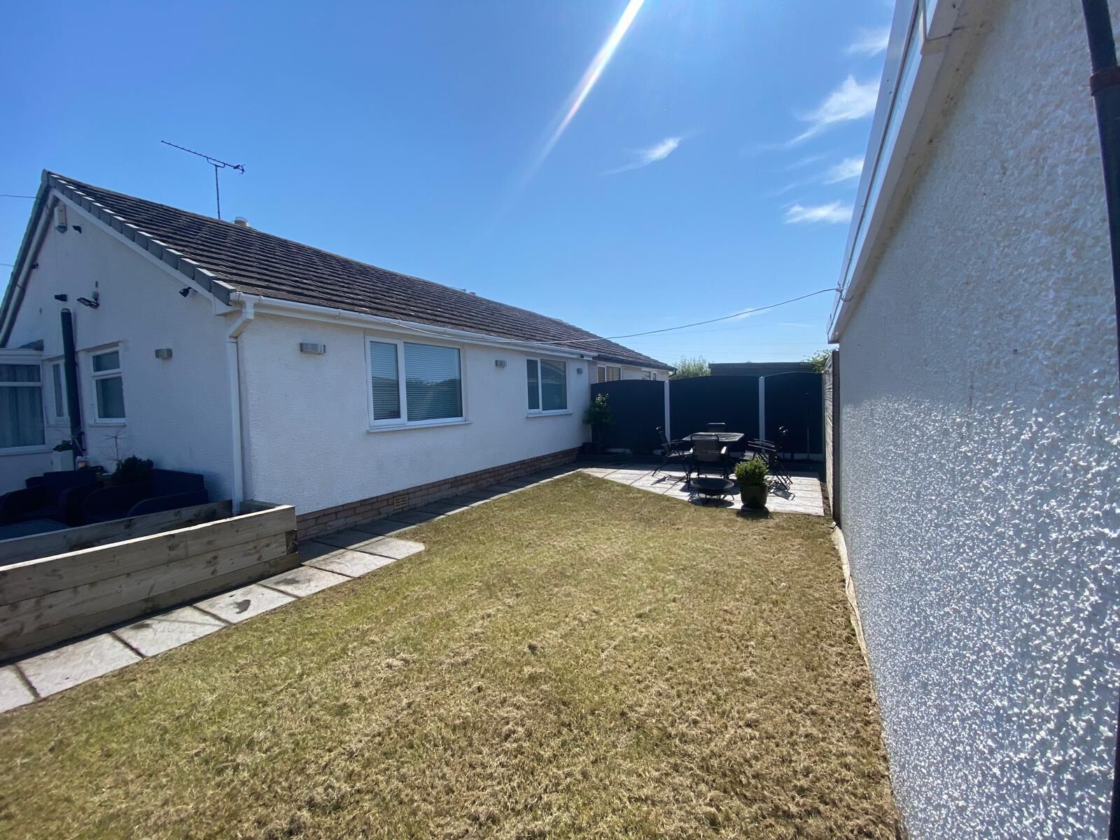 A residential property with a white exterior, a tiled roof, and a small lawn area.