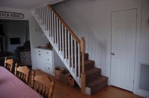 Stairs lead to an upper floor, flanked by white walls and railings, with a door and sign reading 'EACH HOUSE' in the background.