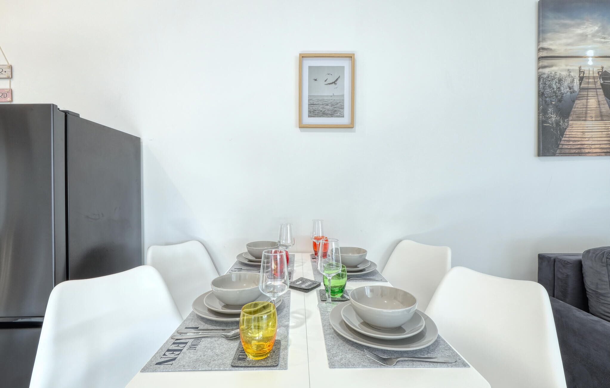 Un comedor con una mesa dispuesta para dos personas, un cuadro en la pared y vista al agua.