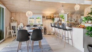 A modern kitchen with wooden accents, a dining area with black chairs, and a bar with stools.