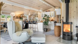 A modern living room with a white sofa, a glass-top coffee table, and a black wood-burning stove.