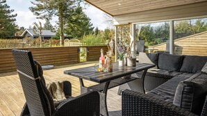 An outdoor patio with wicker furniture, a table with decorative items, and a view of the surrounding landscape.
