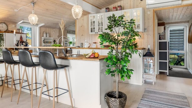 A modern kitchen with wooden accents, a central island with bar stools, and a potted plant.