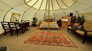 A tent with a bed, a sofa, a table, and chairs.