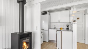 Una cucina moderna con mobili bianchi, un piano cottura nero con fiamma visibile e una piccola isola con lavello e macchina da caffè.