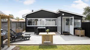 Una moderna casa nera con una terrazza, un barbecue e un giardino.