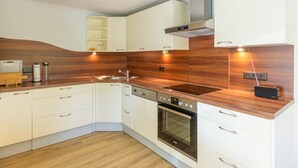 A modern kitchen with white cabinetry, a wooden countertop, a built-in oven, and a microwave. - Awesome home in Wies with WiFi (Wies)
