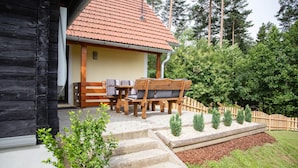 A wooden cabin with a tiled roof, a patio with outdoor furniture, and a garden with steps leading up to the entrance. - Awesome home in Wies with WiFi (Wies)