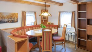 A cozy dining area with a round table, striped cushioned seating, a hanging light fixture, and a wooden bookshelf. - Awesome home in Wies with WiFi (Wies)