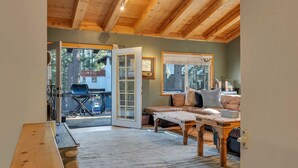 Una habitación acogedora con techo de madera, un sofá, una mesa y un ventanal corredizo que da al exterior.