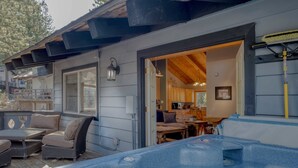 Un espacio al aire libre techado con un jacuzzi, asientos y una terraza de madera.