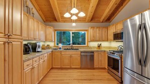 Una cocina moderna con armarios de madera, electrodomésticos de acero inoxidable y un amplio ventanal con vistas al bosque.