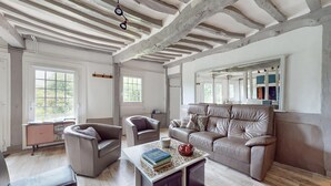 A spacious living room with a large leather sofa, two armchairs, a coffee table with books and apples, and a wooden floor. - 3 bedroom nice home in Vittefleur (Vittefleur)