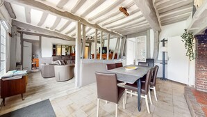 A spacious dining area with a large table and chairs, a kitchen in the background, and a high ceiling with exposed beams. - 3 bedroom nice home in Vittefleur (Vittefleur)
