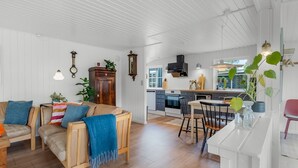 A spacious living area with a sofa, a dining table, and a kitchen in the background.