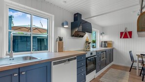 A modern kitchen with a large island, built-in appliances, and a view of the outside.