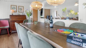 A dining area with a wooden table, chairs, a bottle of wine, and a board game.