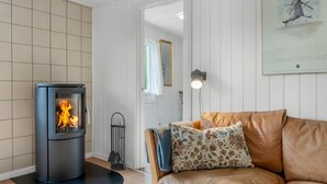 A modern living room with a wood-burning stove, a leather sofa, and a framed artwork on the wall.