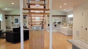 A spacious living area with a wooden ceiling, built-in shelving, a sofa, a TV, and a kitchen area with a refrigerator. - Updated 2 Floor Central Downtown Raleigh Home (Raleigh)
