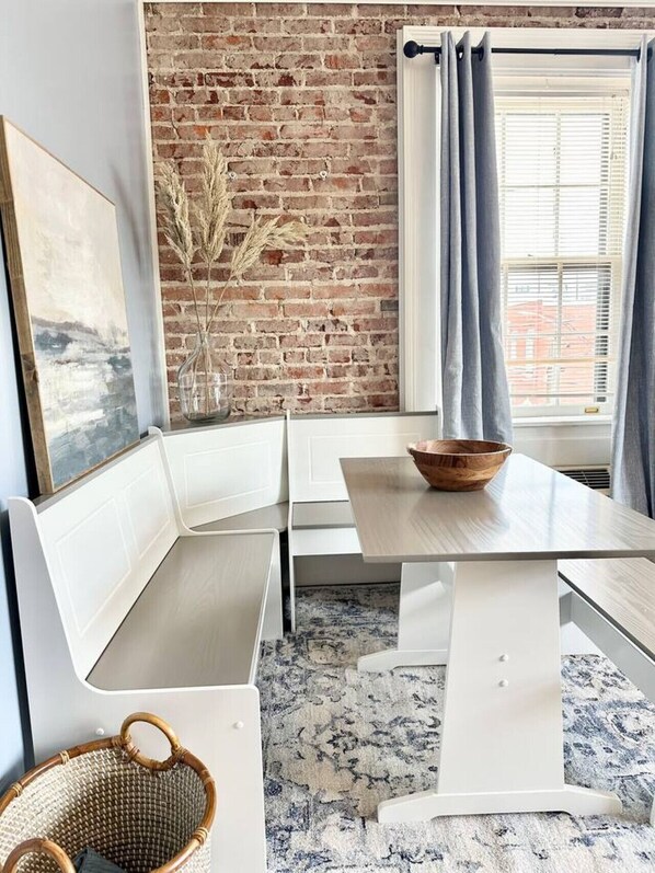 Cozy retreat with a rustic touch, featuring a white bench, dining table, and woven basket.