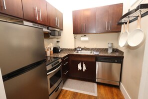 Compact kitchen equipped with a refrigerator, microwave, stove, and dishwasher, along with a sink and coffee maker.