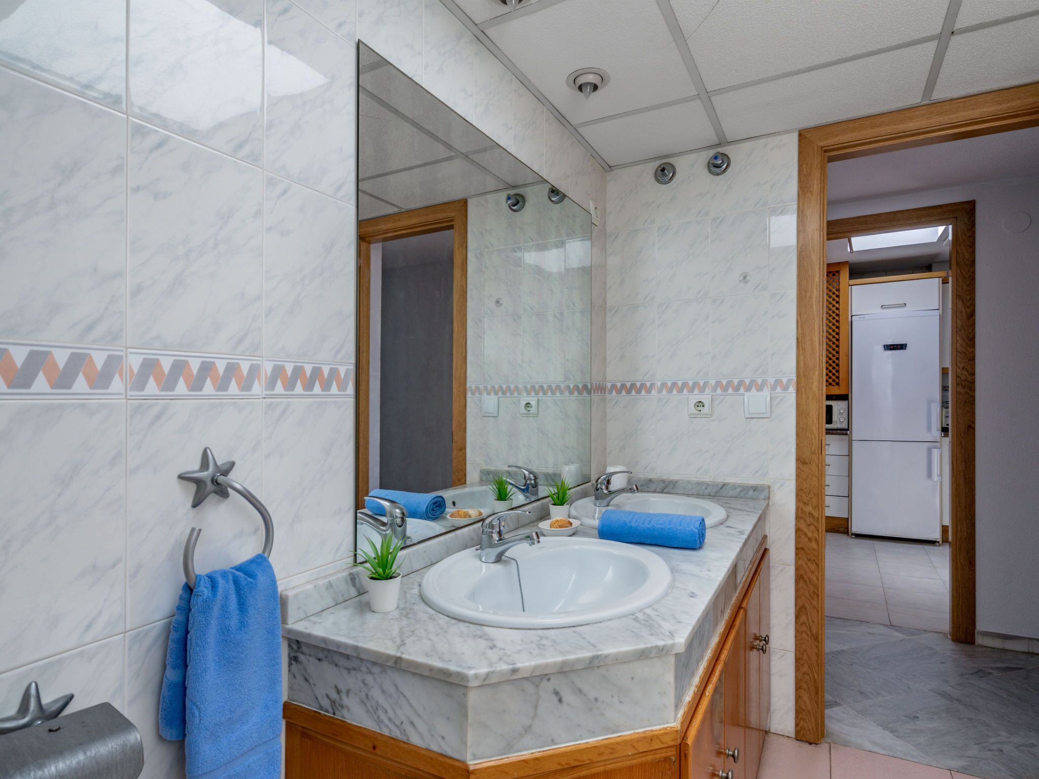 A bathroom with a marble sink, a mirror, a towel rack, and a shower.