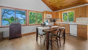 A kitchen with wooden cabinets, a dining table with chairs, a microwave, and a dishwasher.