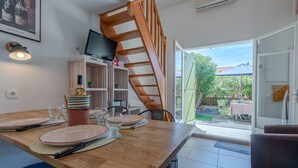 Une cuisine moderne avec un escalier en bois, une table à manger dressée avec des assiettes et des verres, et un téléviseur fixé au mur.