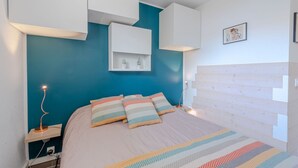 Une chambre moderne avec un mur d’accent bleu, une tête de lit en bois et un lit avec une literie à rayures.