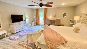 A bedroom with a large bed, a ceiling fan, a TV, a dresser, and a chair. - Downtown+FreePark+Wifi Main St. Ste 201 (Eureka Springs)