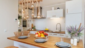 A modern kitchen with a wooden island, hanging light fixtures, and a fruit bowl.