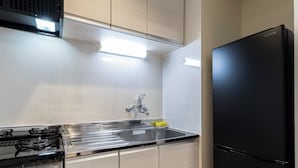Une cuisine moderne dotée d’appareils électroménagers en acier inoxydable, d’un réfrigérateur noir et de meubles de couleur claire.