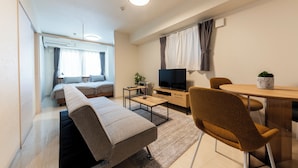 Un salon moderne comprenant un canapé, une table basse, un téléviseur et un coin repas avec une table et des chaises.