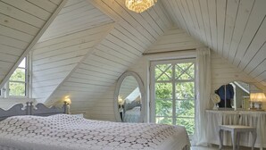 Un dormitorio con una cama grande, un tocador con espejo y una araña.
