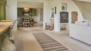 Un amplio salón con una mesa de comedor de madera, un sofá blanco y una araña.